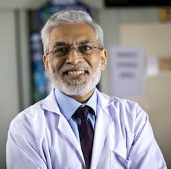 Male physician in white jacket smiling.