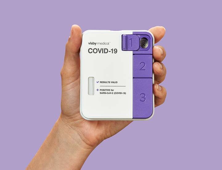 A hand holds up a Visby Medical COVID-19 PCR device.