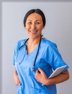 Smiling female nurse in blue scrubs.