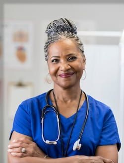 Smiling female nurse in blue scrubs.